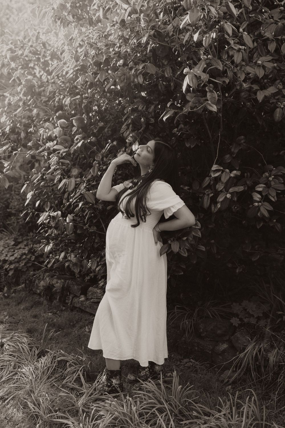 A moody black and white photo series shows a figure in white standing against a leafy garden backdrop.