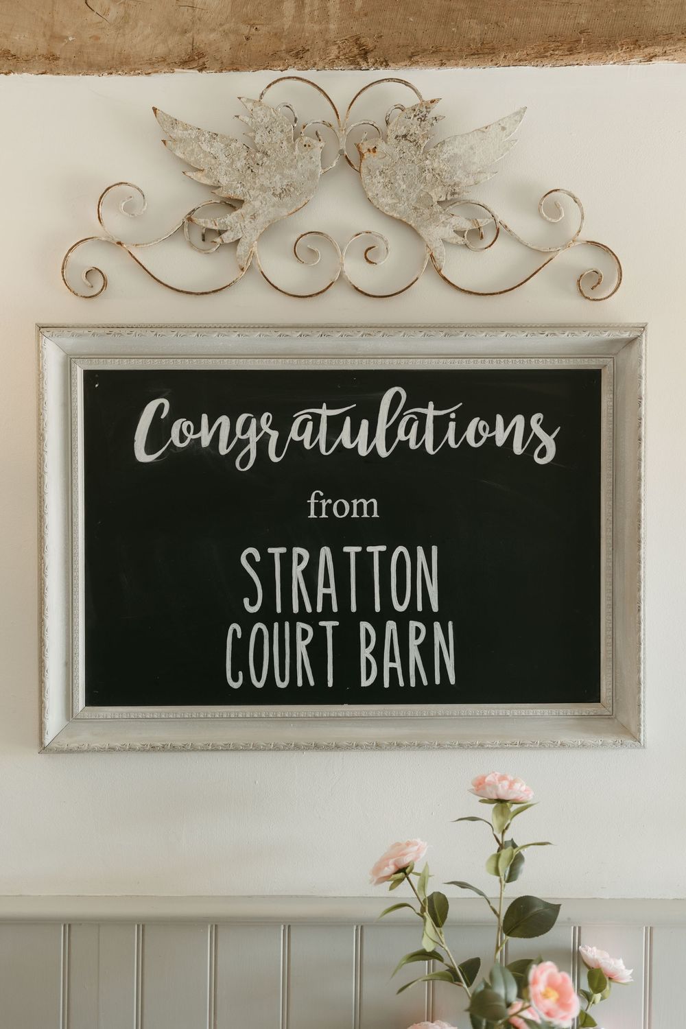 A rustic welcome sign reading 'Congratulations from Stratton Court Barn' with decorative scrollwork and flowers.