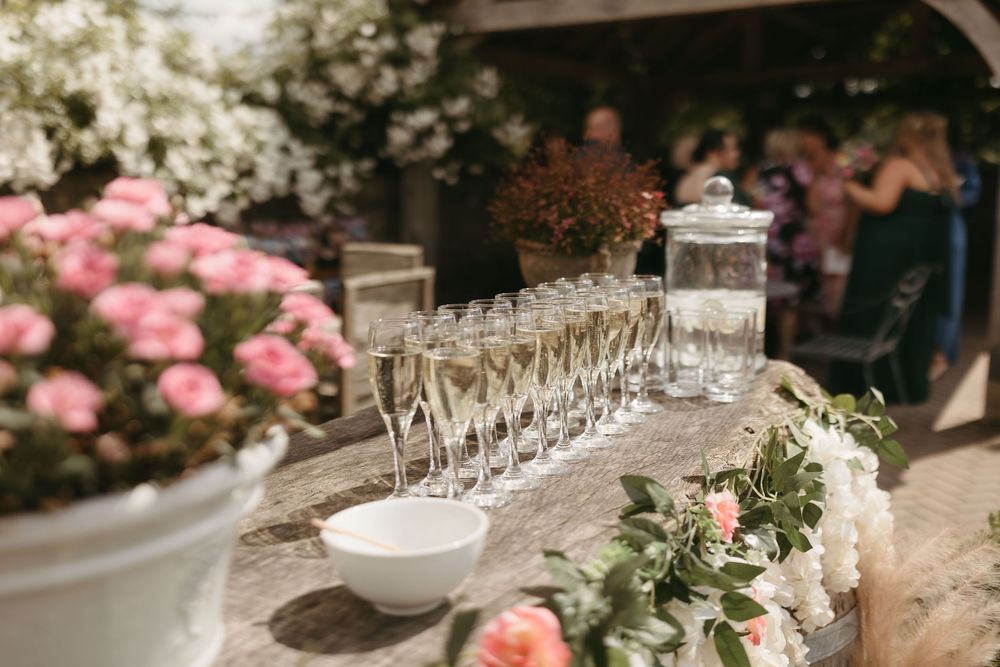 Wedding reception table with champagne glasses and pink floral arrangements.