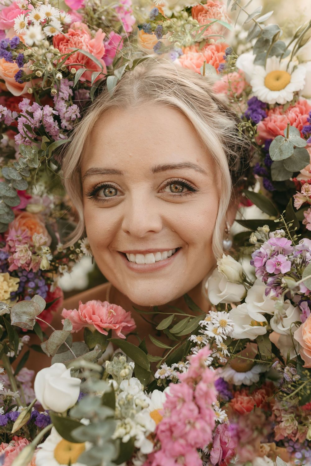 A joyful portrait framed by a stunning array of colorful spring flowers including roses, daisies and eucalyptus.