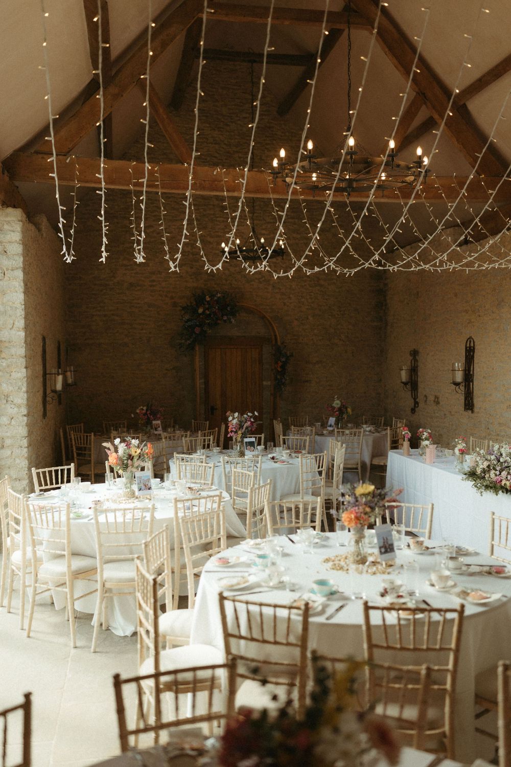Elegant wedding reception venue with string lights and white chiavari chairs.