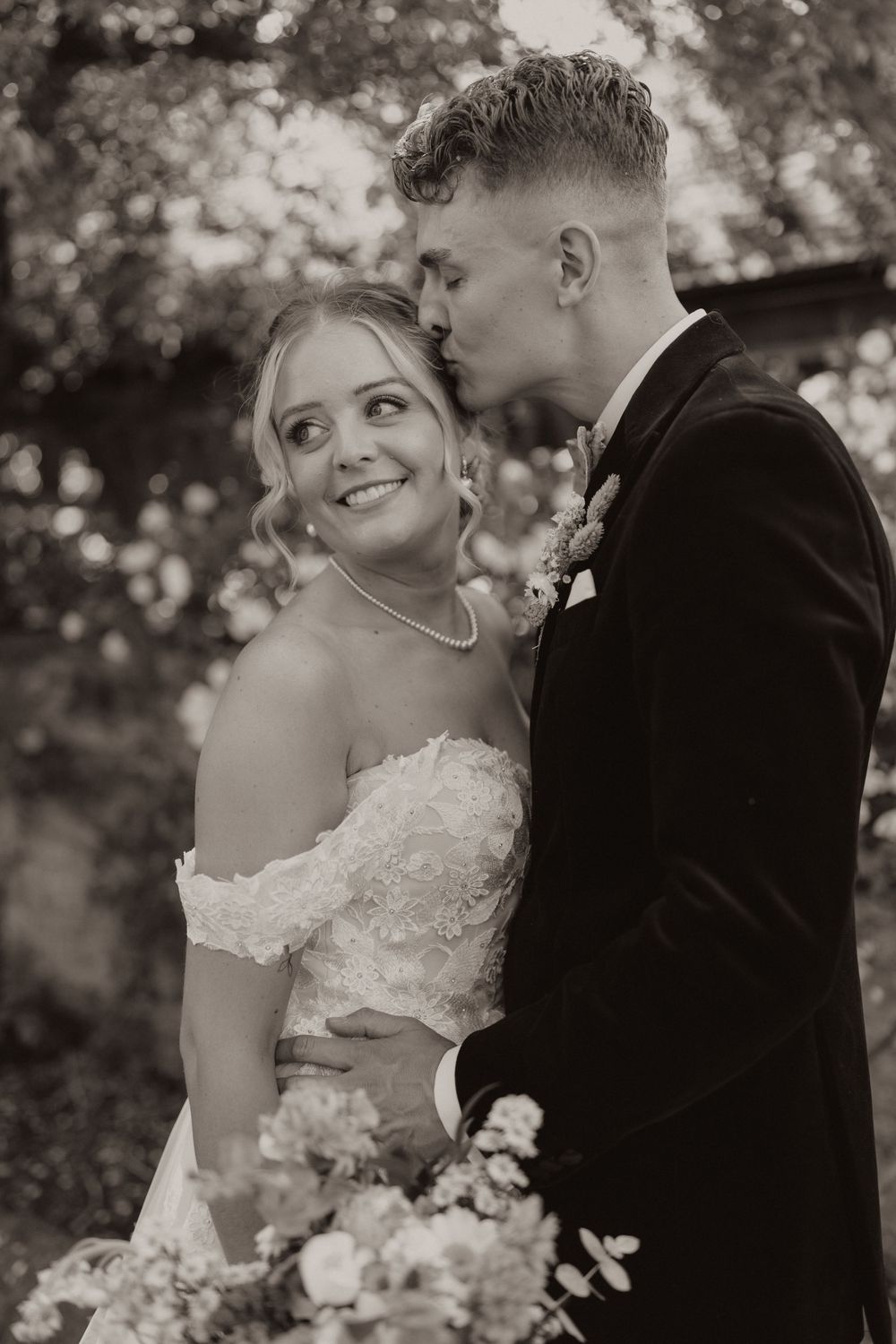 Intimate black and white wedding portrait in a garden setting.