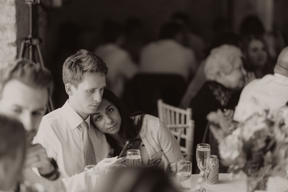 A vintage black and white photograph shows guests seated at table during a wedding reception.