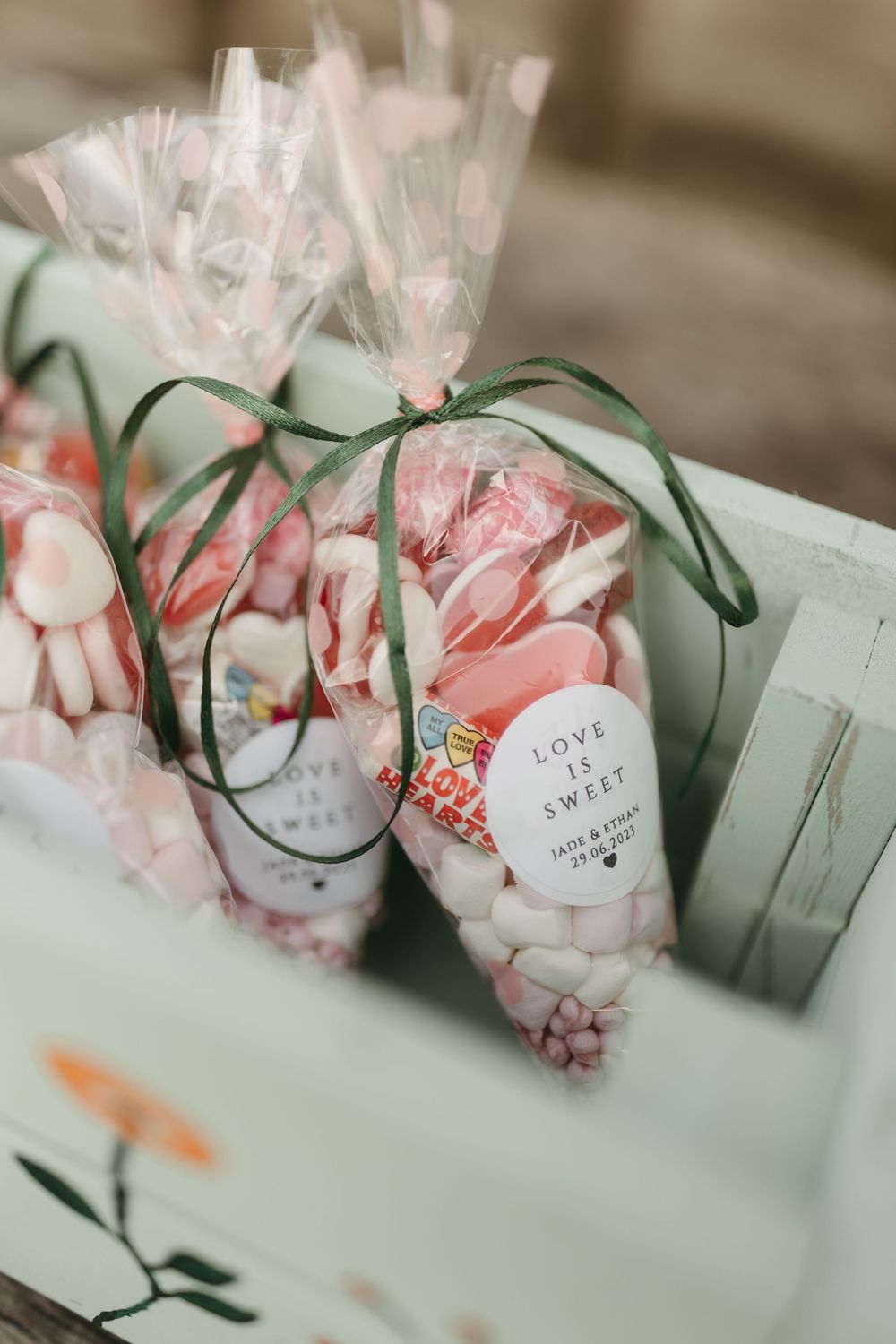 Wedding favor bags filled with treats and tied with sage green ribbons.