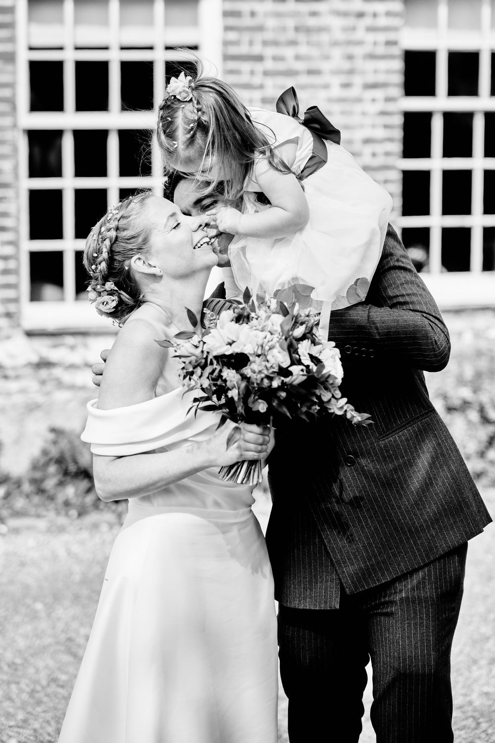 A joyful wedding moment captured in black and white as two people share a moment with their wedding bouquet.