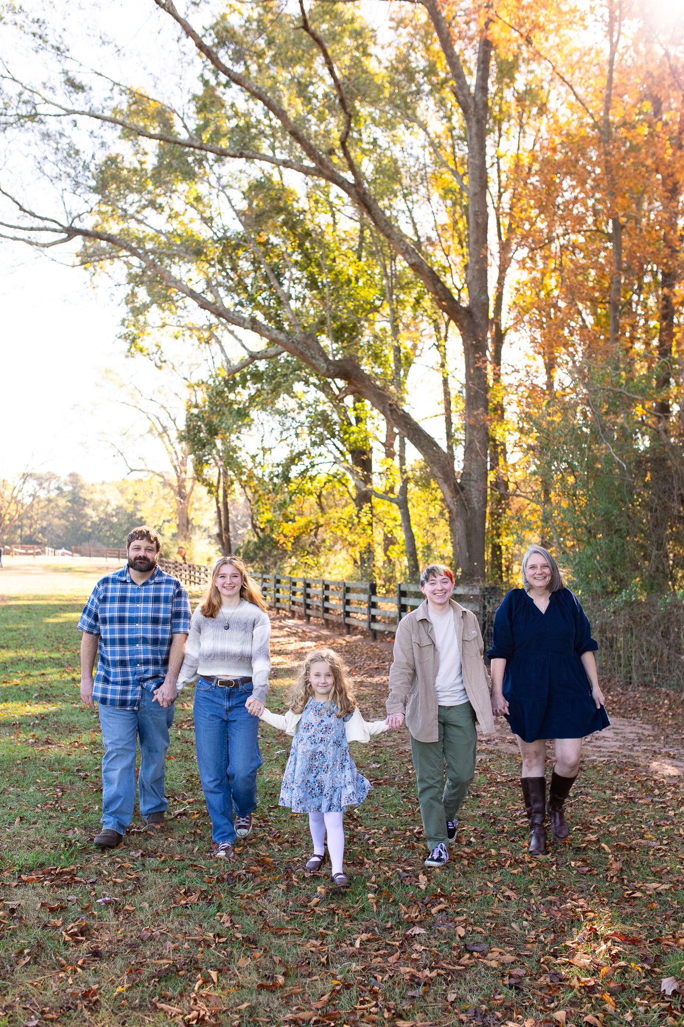 Family walk along a wooden fence path surrounded by colorful fall foliage at Sugg Farm