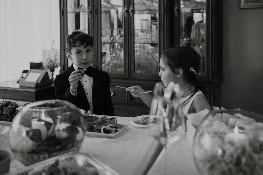 A vintage black and white photo of a couple enjoying drinks at a formal dining table.