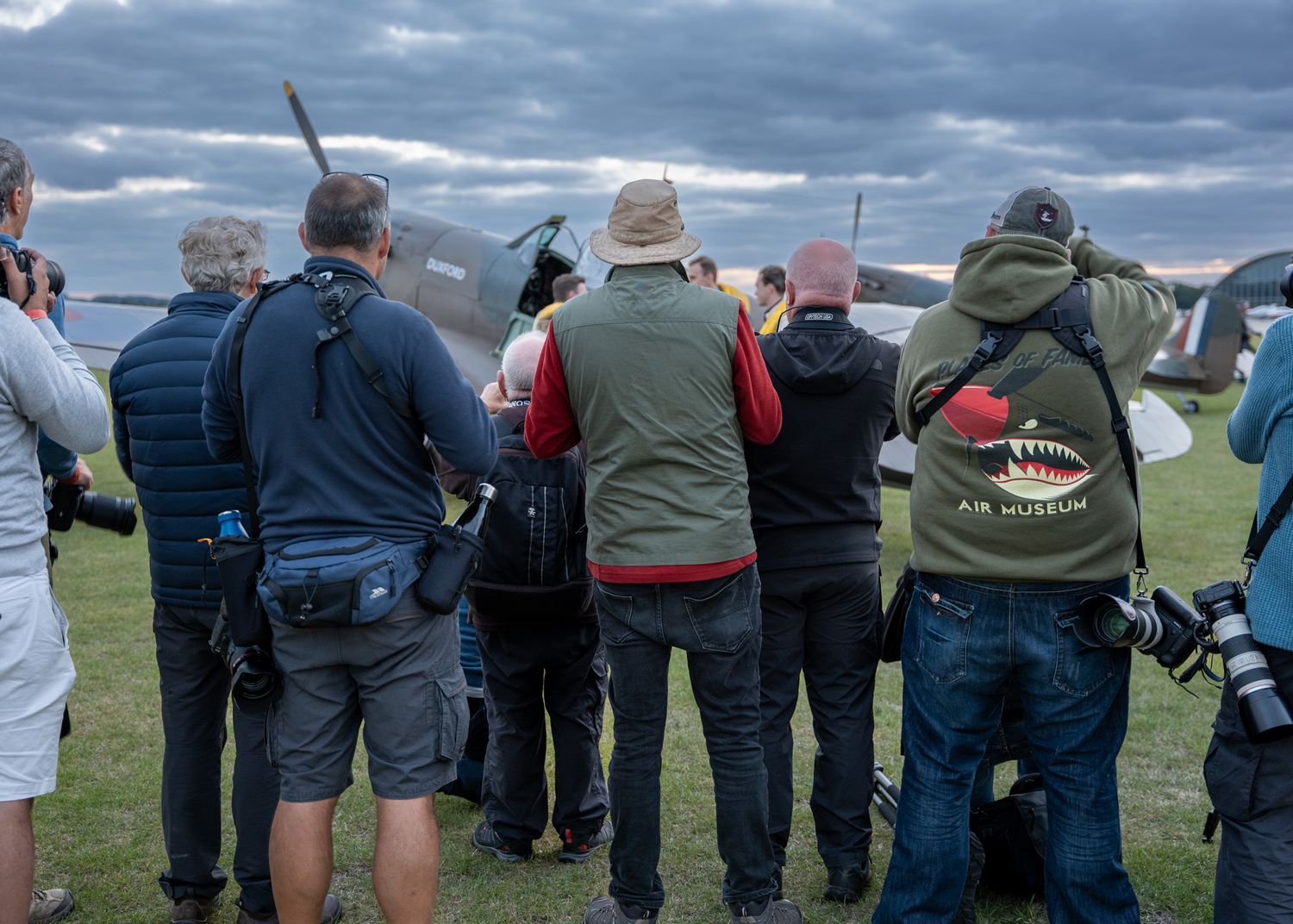 Crowd of photographers and spectators viewing aircraft at an outdoor aviation event.