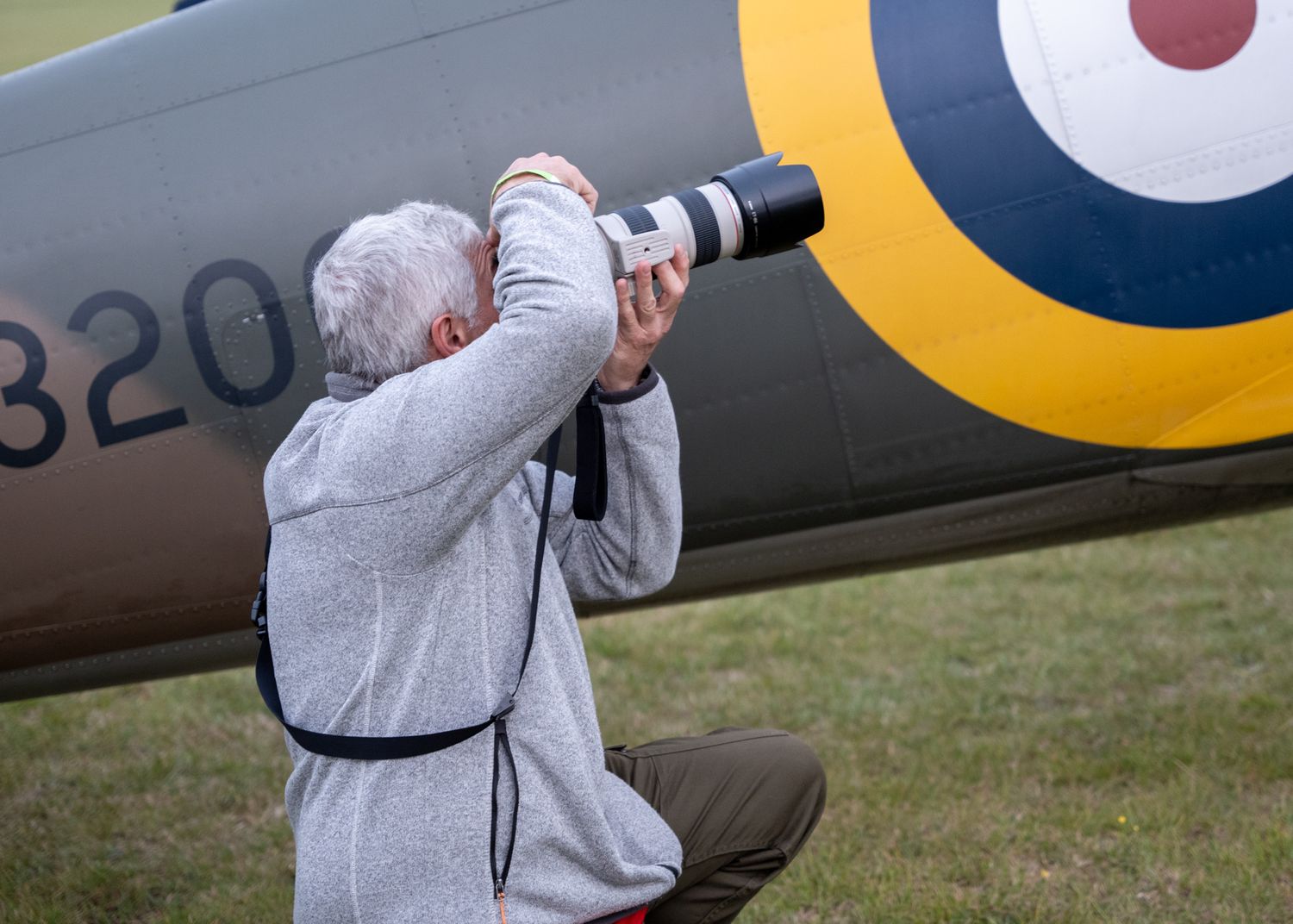 Photographer with telephoto lens capturing images of a vintage RAF aircraft.