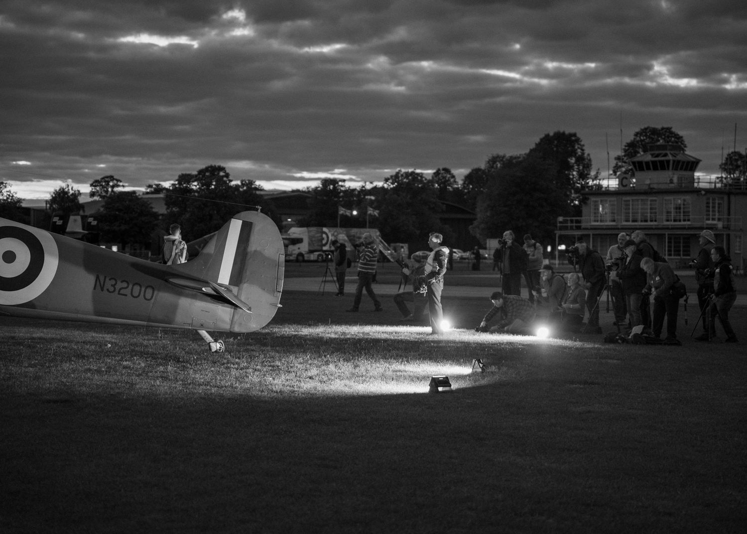 Nighttime airfield scene with illuminated vintage aircraft and ground crew.