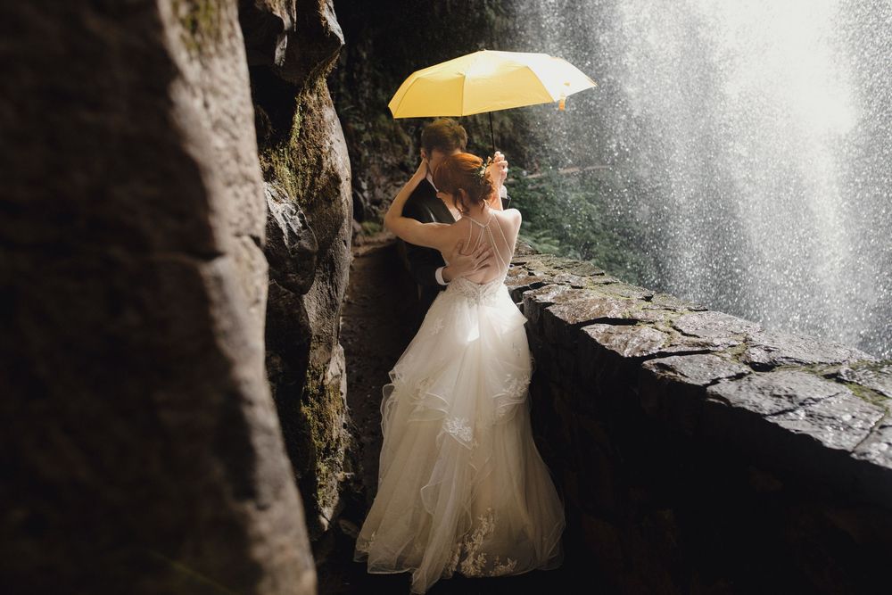 Wedding photoshoot in a rustic tunnel features a bride in a white ballgown dress and veil illuminated by natural light.