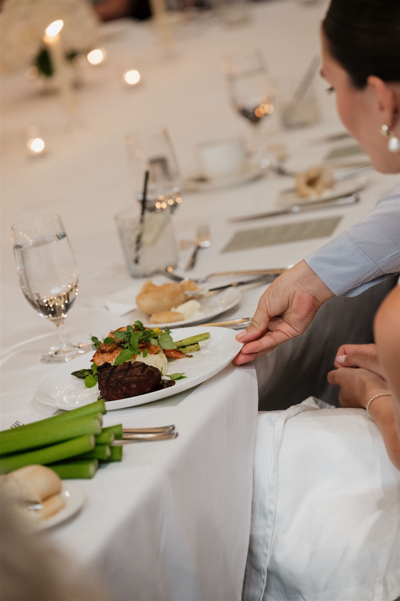An elegant dinner table setting with a plated steak dish, wine glass, and candlelight ambiance at an upscale restaurant.