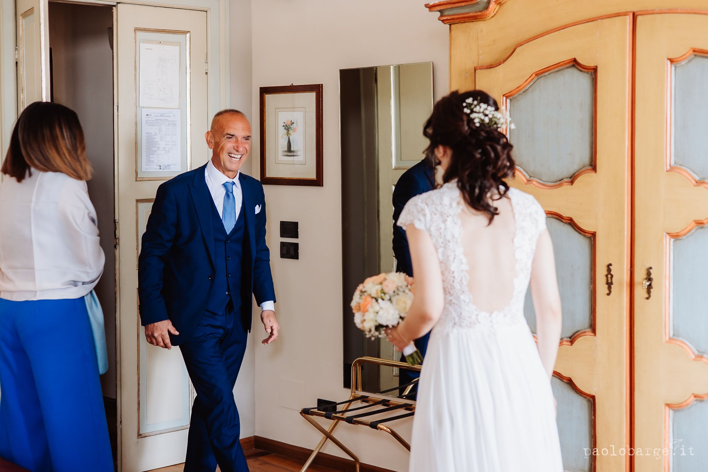A wedding scene in an elegant indoor setting with white dress and navy blue suit details.