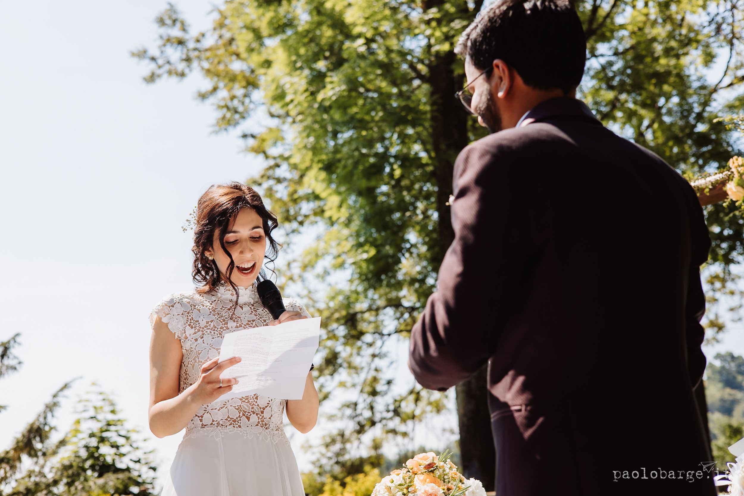 Newlywed couple sharing romantic moments outdoors in sunlit natural setting during wedding photo session.