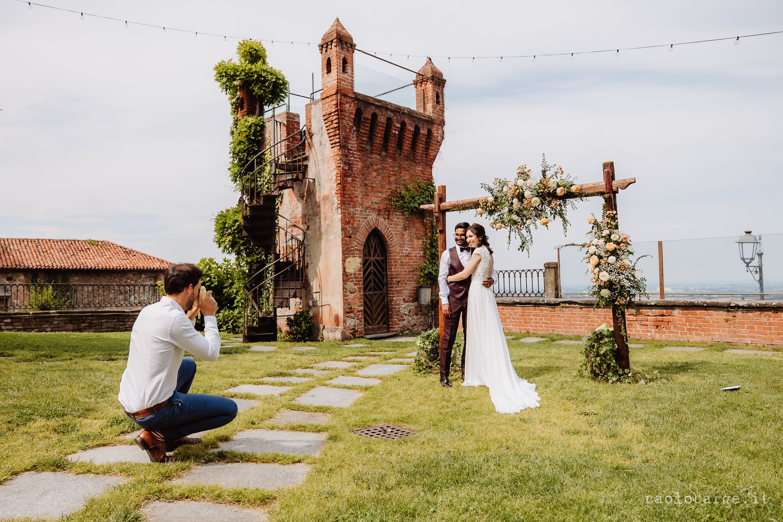 A wedding celebration sequence at a rustic brick church venue with string lights and a stone pathway through green grass.