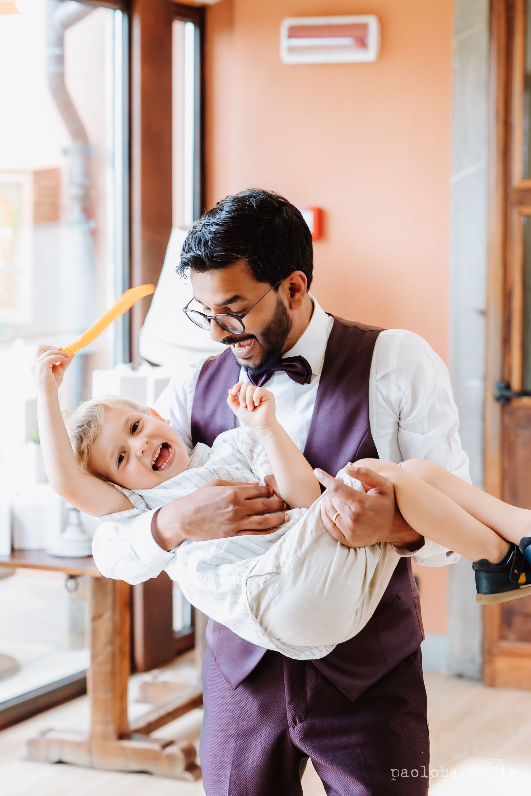 A series of four candid shots showing a parent in a purple vest and white shirt playfully dancing with a baby.