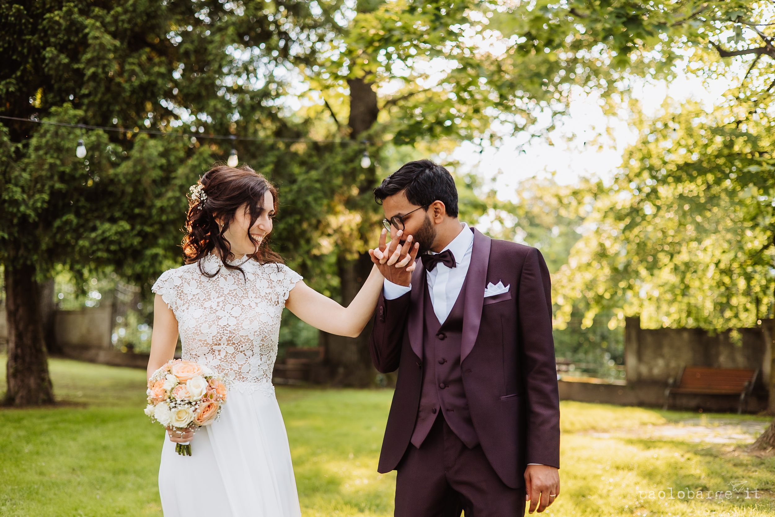 A couple shares an intimate moment in a garden setting during a wedding photo session among sun-dappled trees.