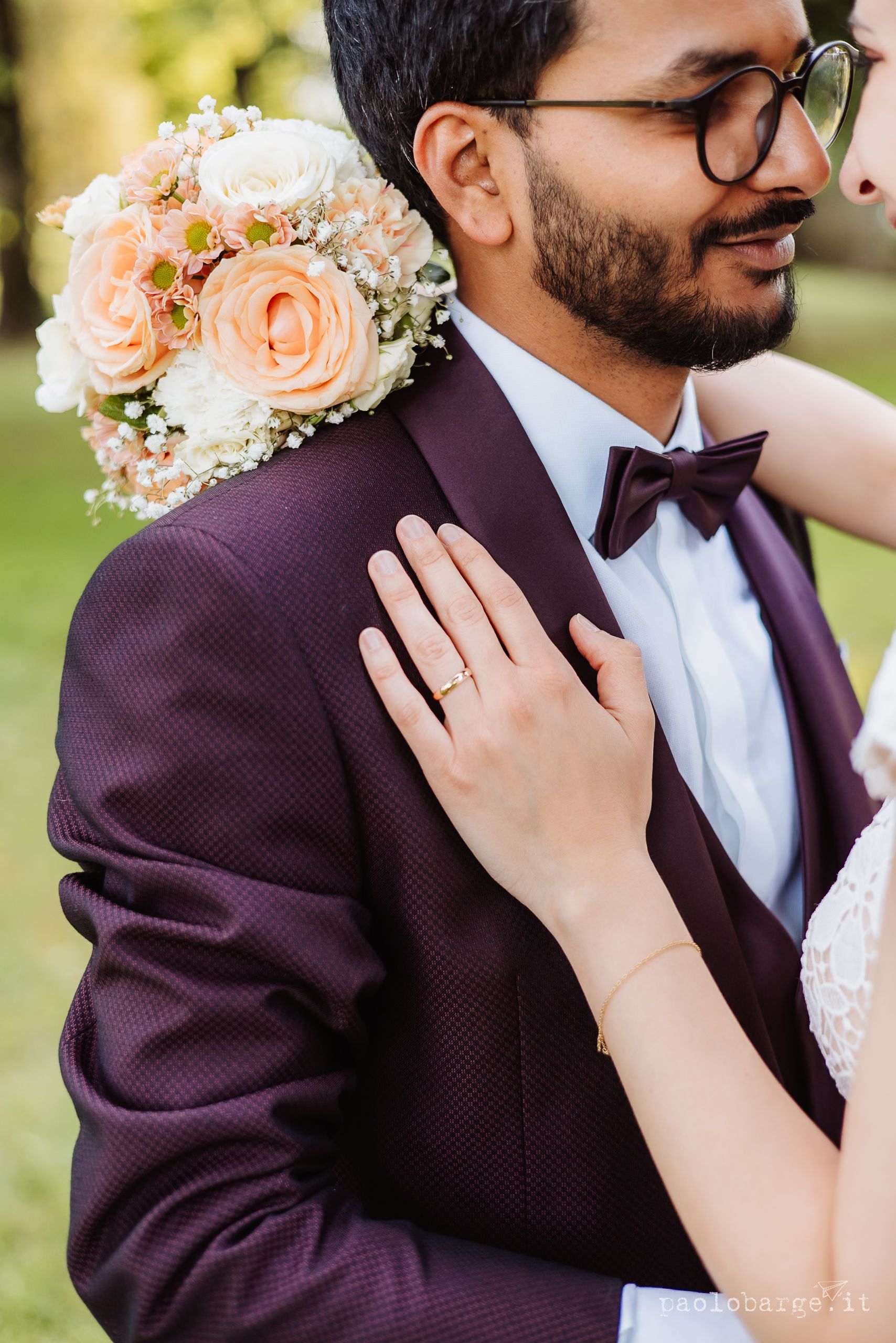Close-up wedding photos showing tender moments between a couple in burgundy and white formal attire with peach roses.