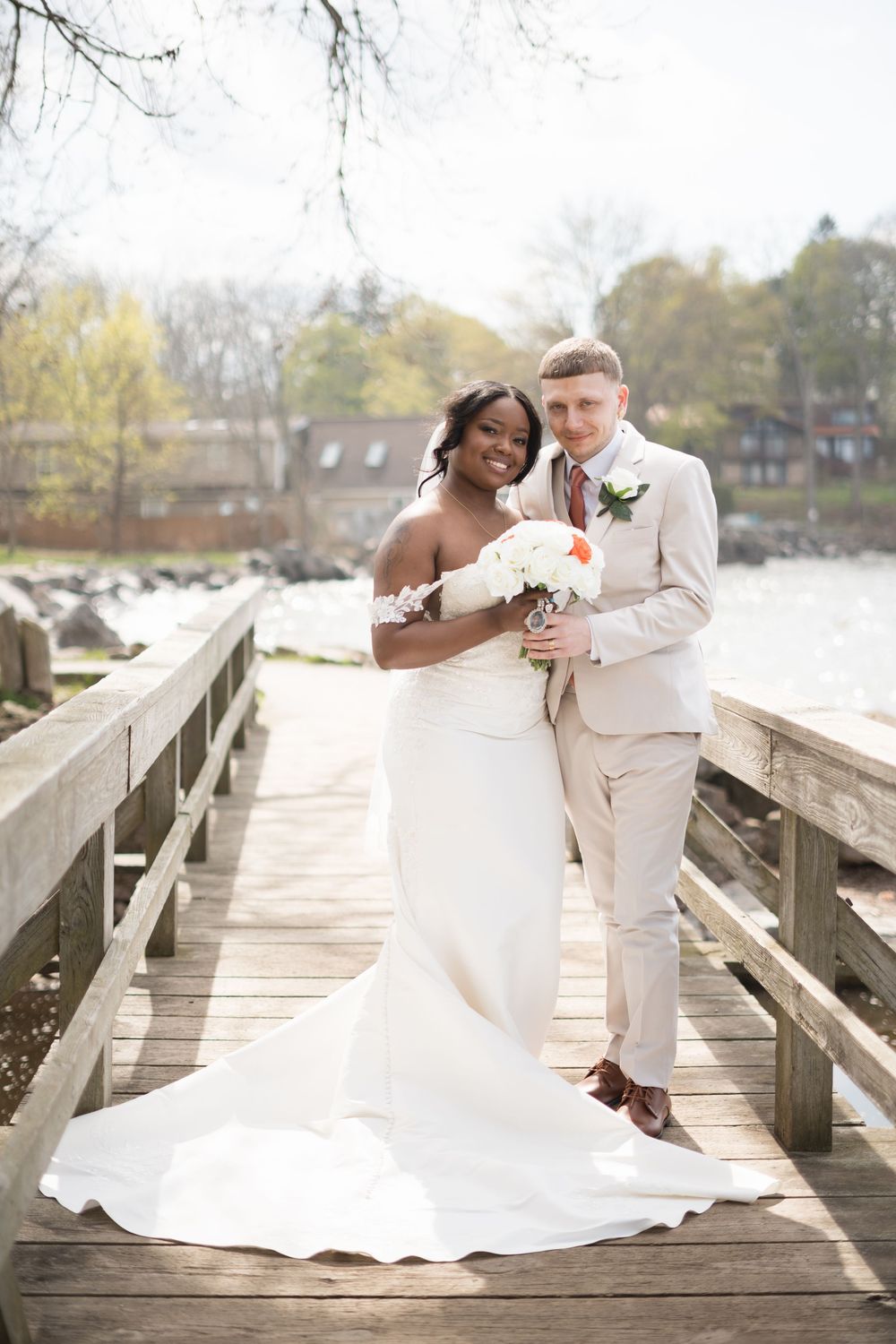 A romantic wedding couple shares an intimate dip pose on a wooden dock by a lake during their autumn celebration.