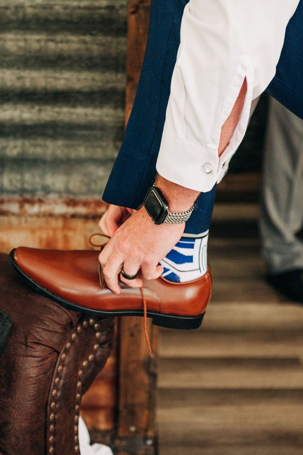 Series of closeup shots showing a brown leather shoe being put on with navy pants and white socks.