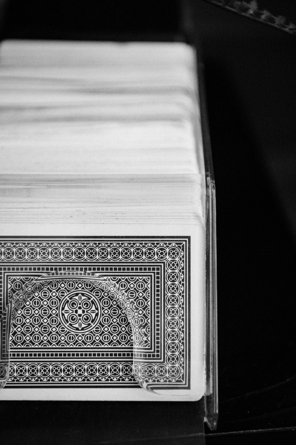 Black and white close-up of ornate vintage playing cards stacked together showing detailed geometric border patterns.