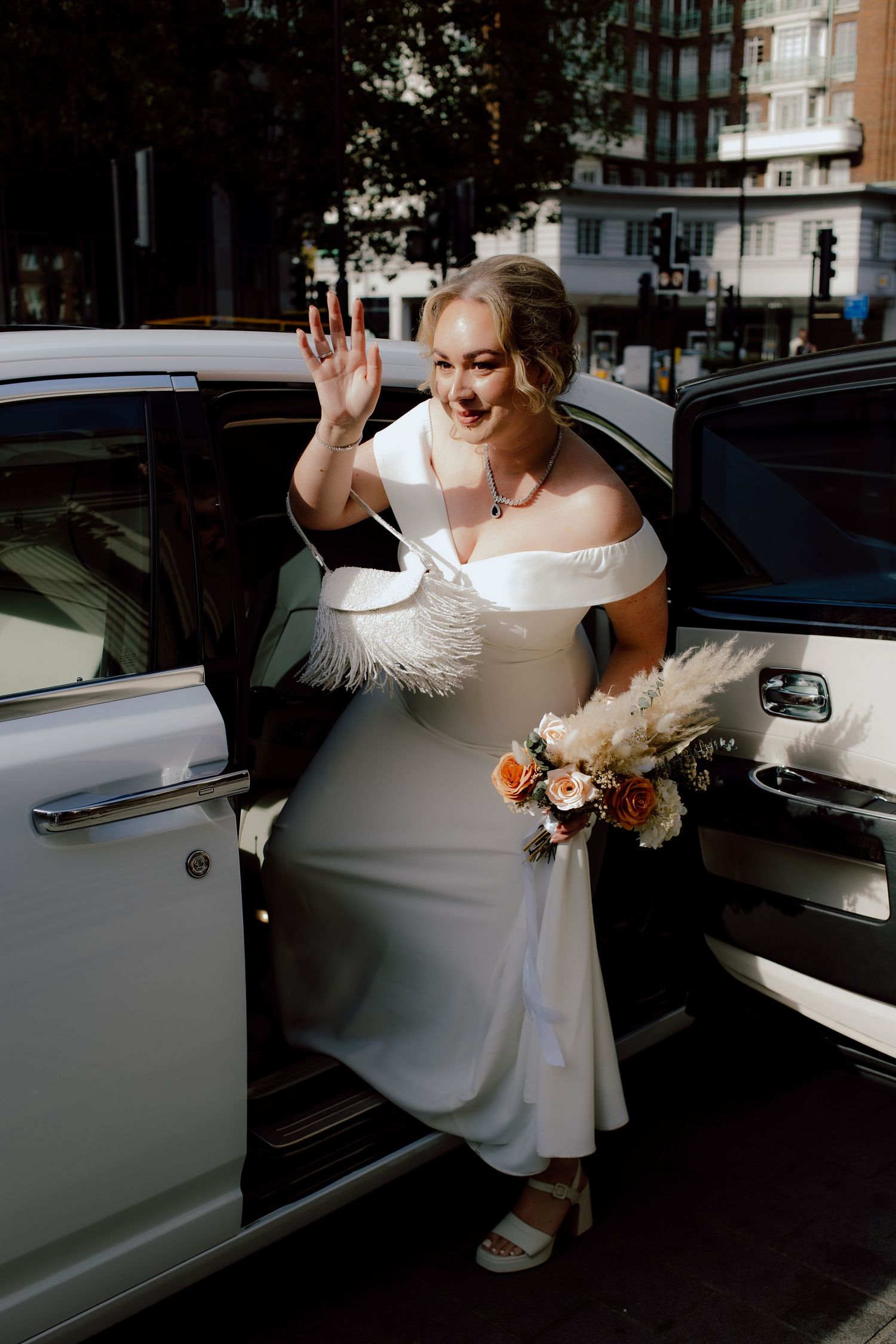 A person in a white wedding dress gracefully enters a vintage black car in a series of elegant poses.