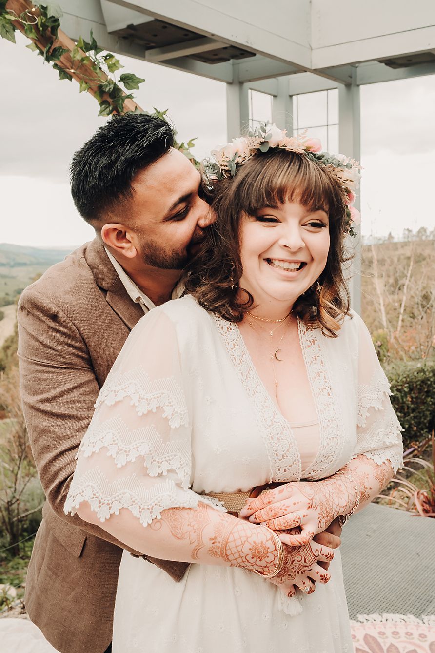 A couple shares an intimate romantic moment together in semi-sheer beige wedding attire on their special day.