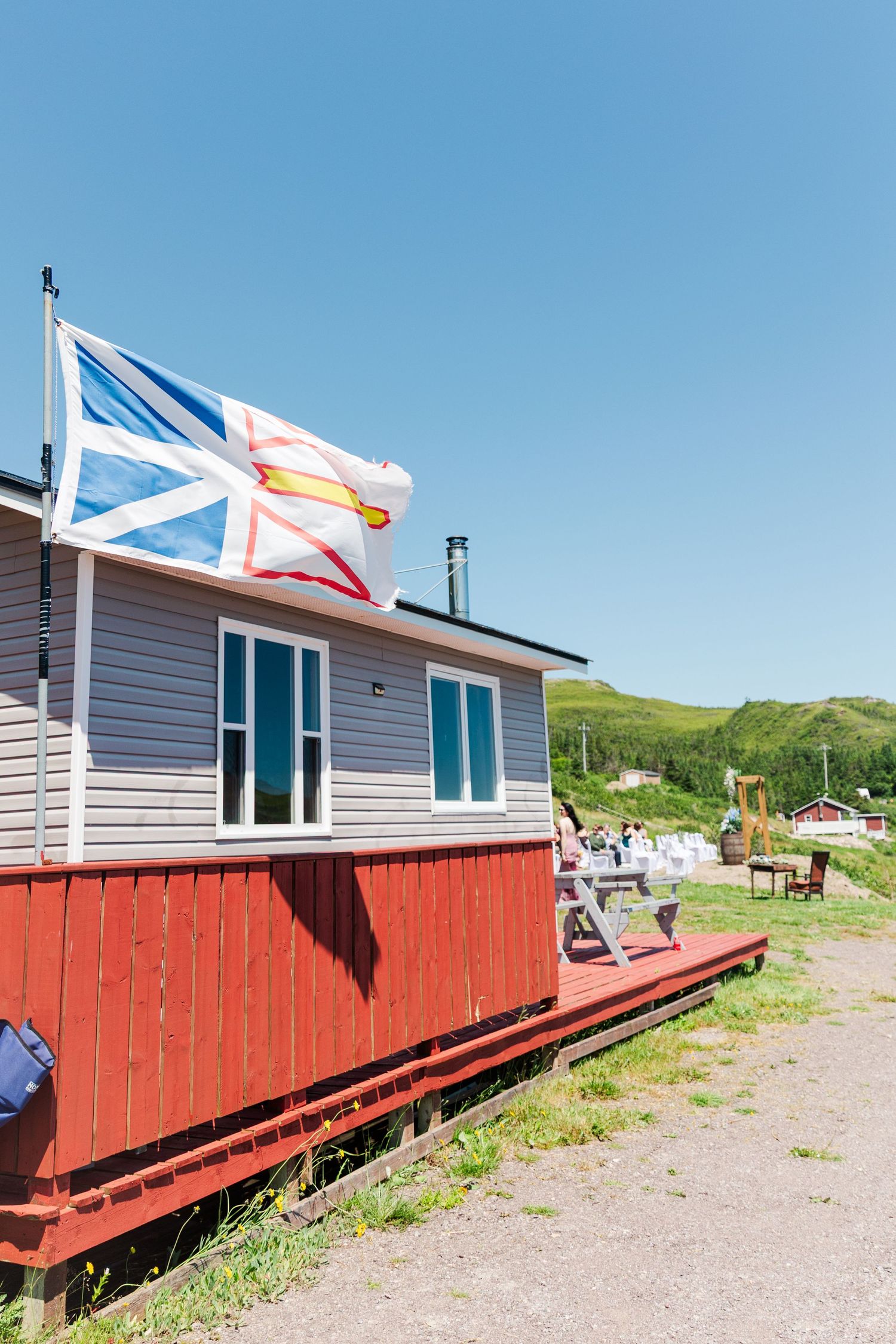 Four connected images showing a red-based building with white top exterior and flags mounted on flagpoles against blue sky.