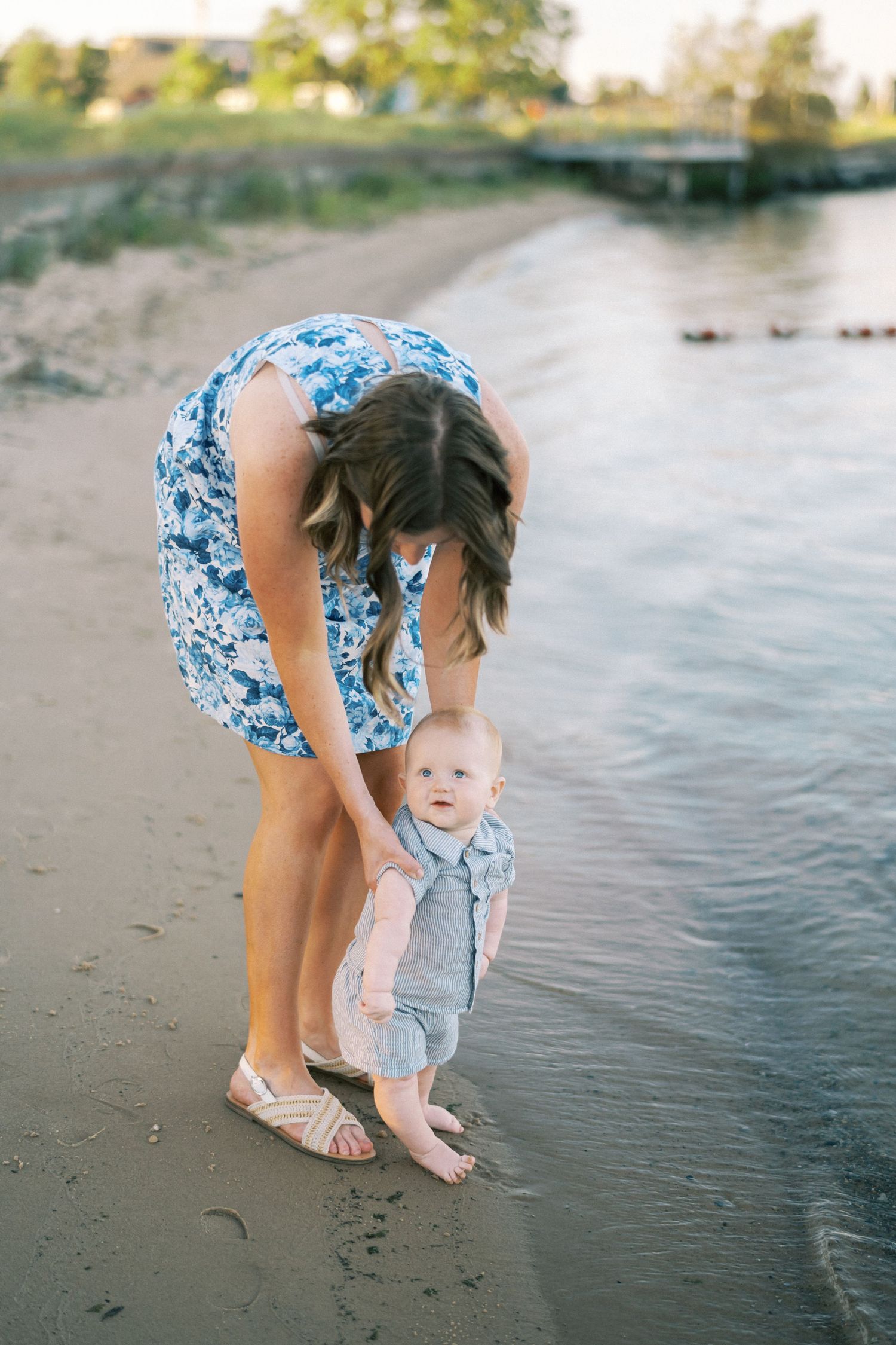 A tender moment between parent and child on a peaceful beach at sunset as they play near the water's edge.