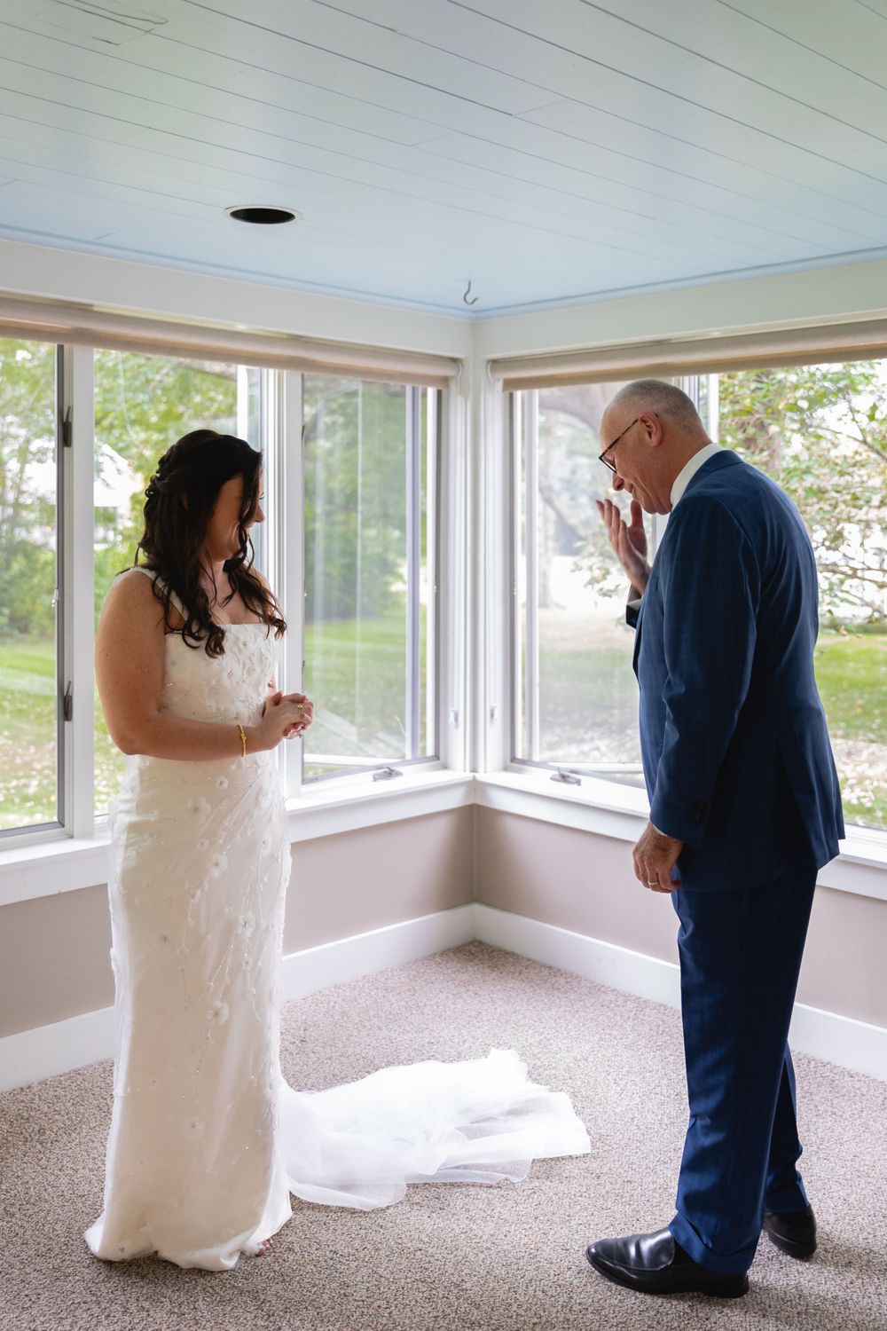 An emotional moment captured in a bright corner room with large windows and carpeted flooring.