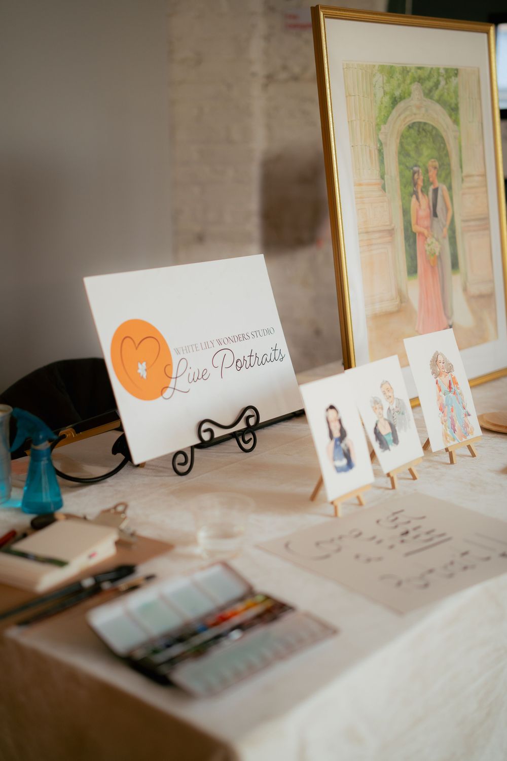 Business cards and art displays on a table showcase branding with orange accents and an elegant easel setup.