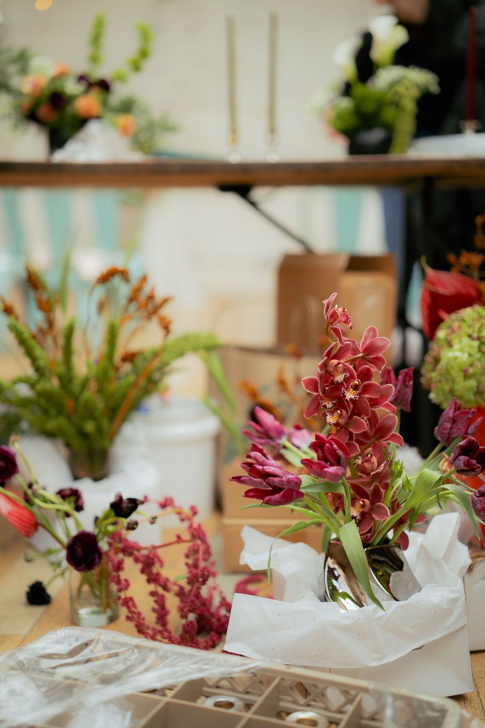 Colorful floral arrangement with pink blooms and greenery displayed on a table with tissue paper.