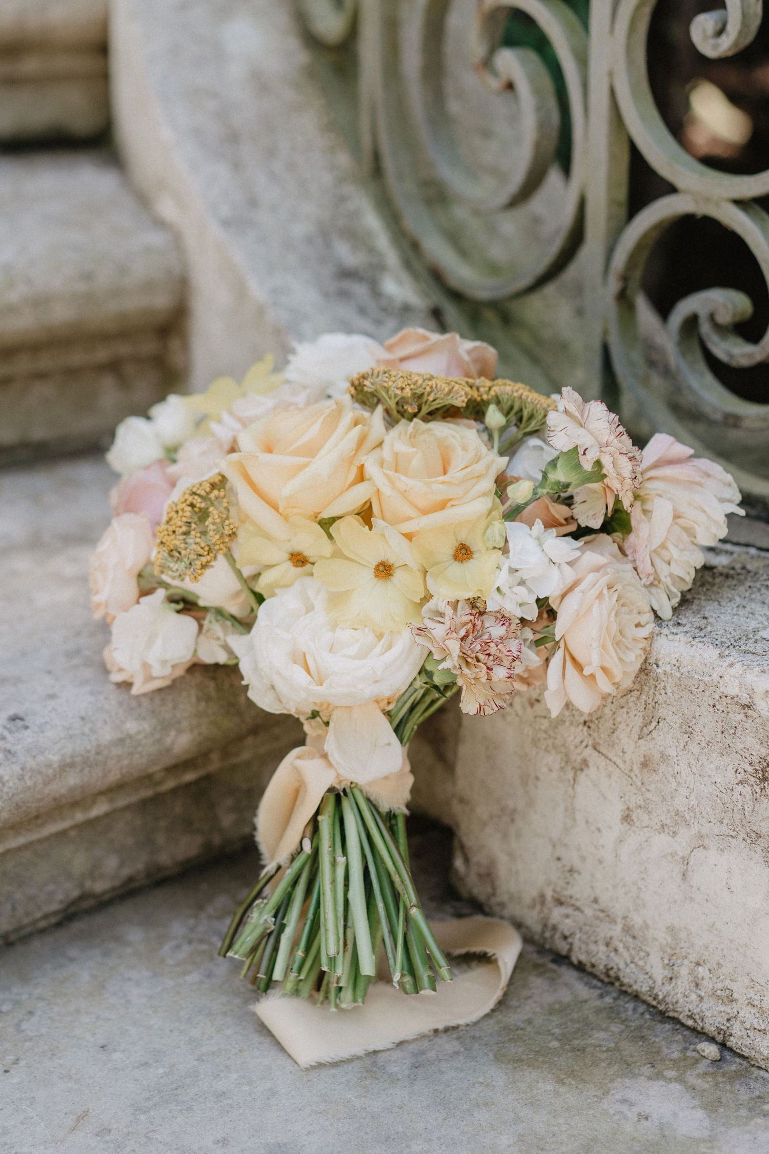 Romantic peach and cream rose bouquet with delicate details resting on stone steps.