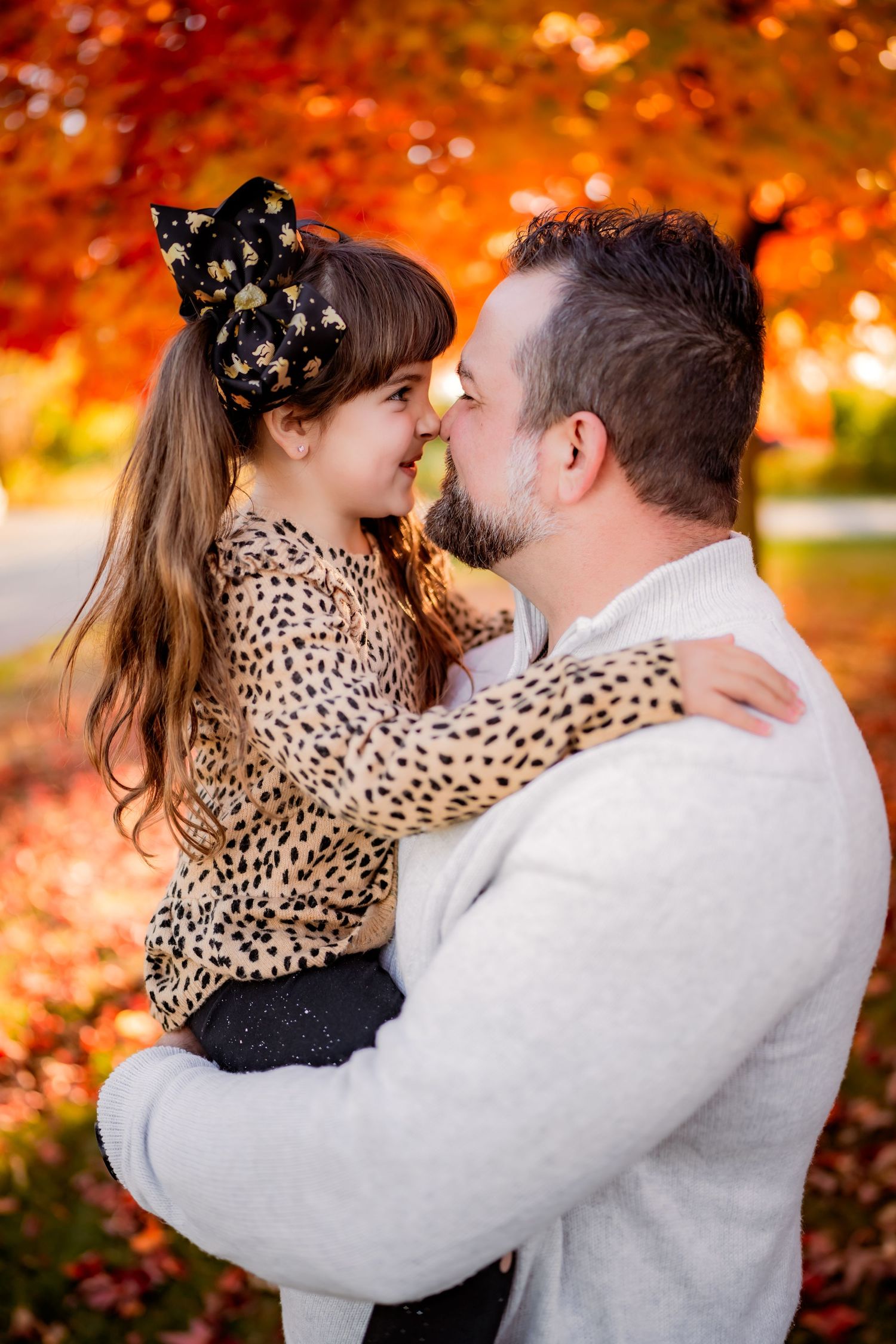 Tender autumn portrait captured during golden hour with vibrant fall foliage and matching leopard print sweater.