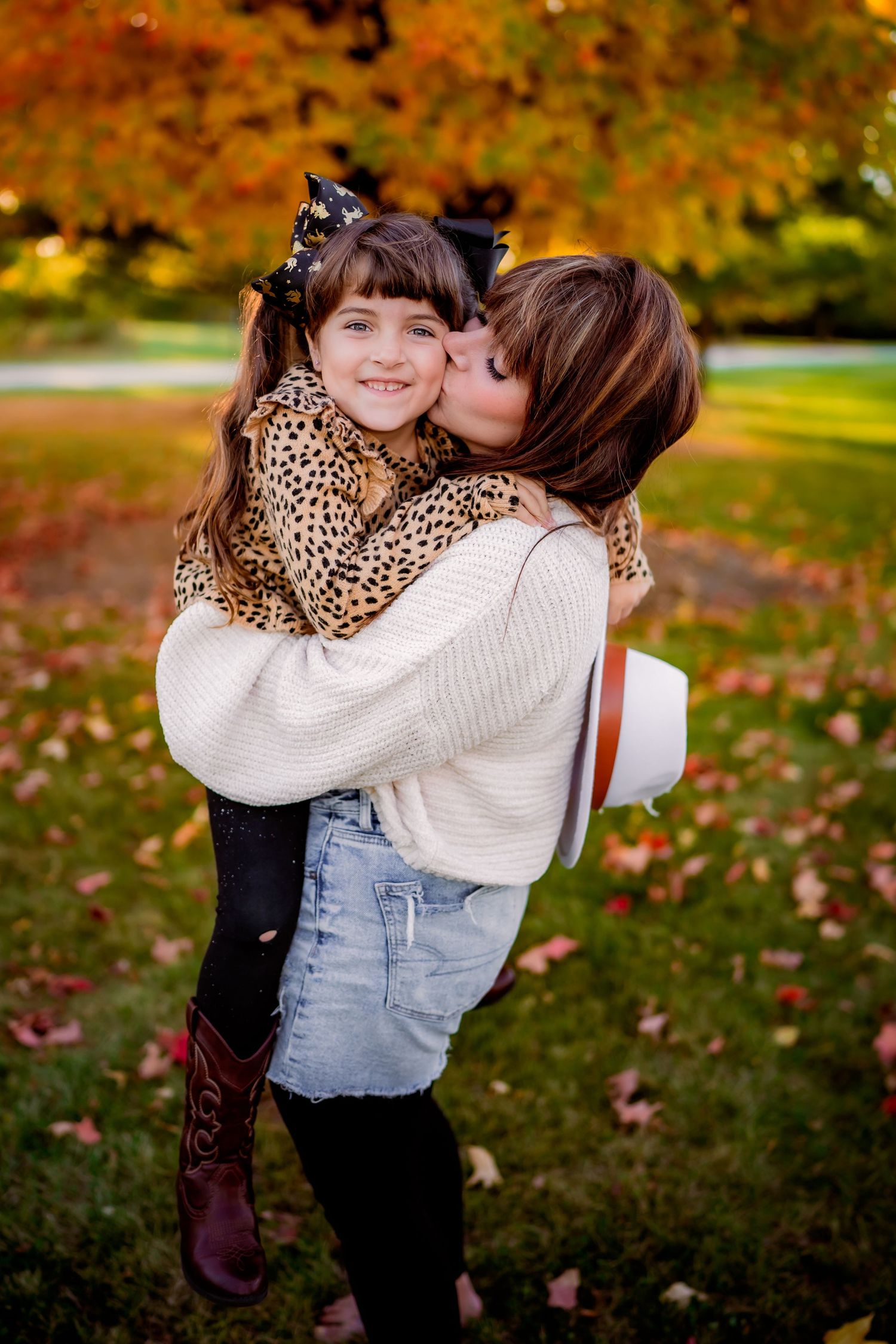 A sweet autumn moment captured outdoors with a loving embrace among colorful fall foliage in the background.