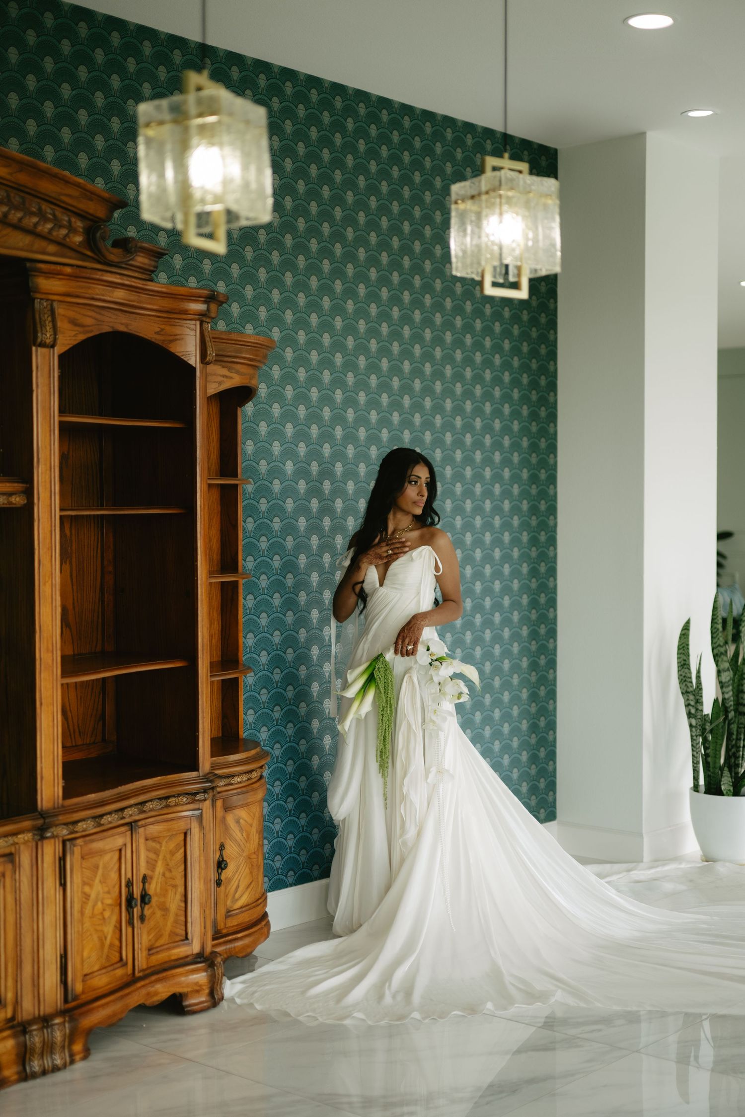 Black and white photo of an elegant wedding gown with off-shoulder bow sleeves and full skirt in a garden setting with gazebo.