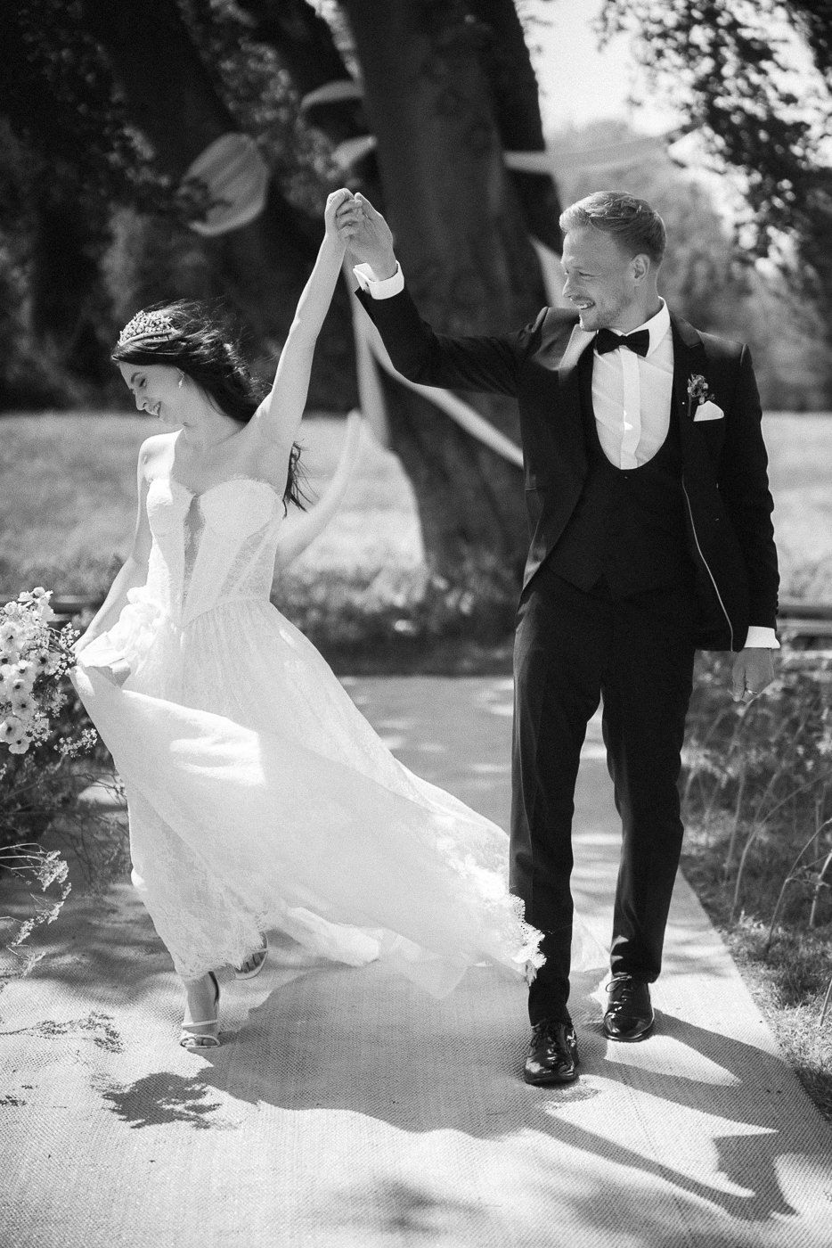 Couple taking a stroll through a field in formal wedding attire.