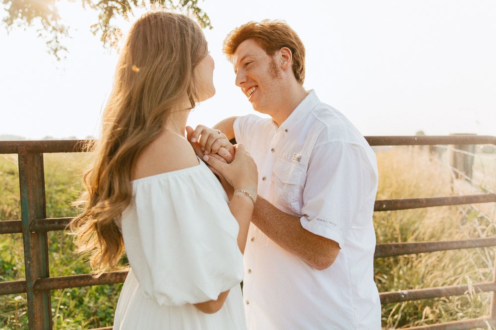 Romantic couple sharing intimate moment on sunlit balcony in white outfits.