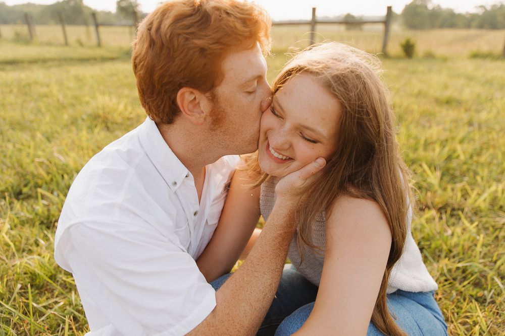Intimate moment between couple in grassy field during sunset in Lexington, Kentucky.