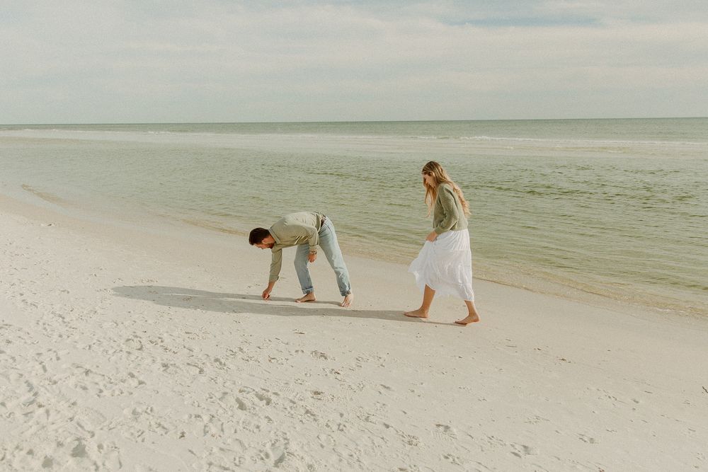 Two people walking on pristine white sandy beach by ocean in Panama City Beach, Florida.
