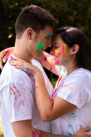 Couple covered in colorful powder paint embrace during a Holi celebration photoshoot.