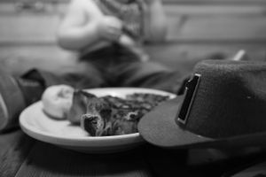 A black and white photo of a steak dinner with a cowboy hat on a wooden table.