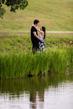 Romantic portrait by a tranquil pond with tall grasses and natural reflections in the water.