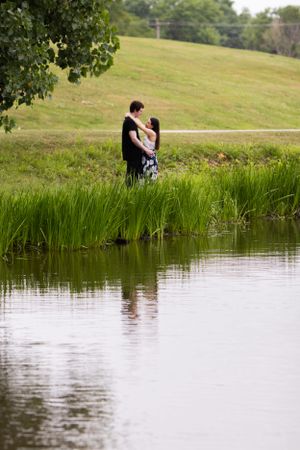 Serene lakeside portrait with green grass and water reflections creating peaceful nature composition.