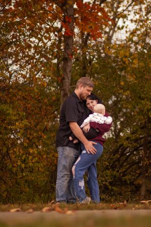 A family shares an intimate moment together on an autumn path surrounded by colorful foliage.