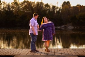 A couple shares a romantic moment on a wooden dock at sunset.