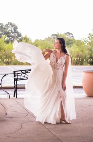 Flowing white wedding gown with lace bodice billowing in breeze during outdoor bridal photoshoot.