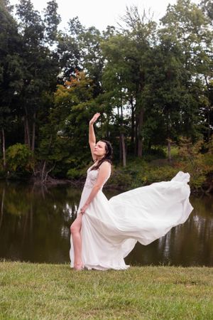 Ethereal bridal portrait with flowing white dress against lakeside backdrop.
