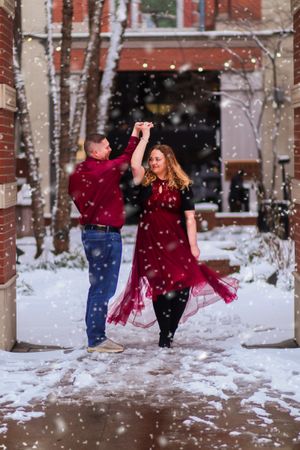 A couple dancing in the snow with the woman wearing a flowing red dress.