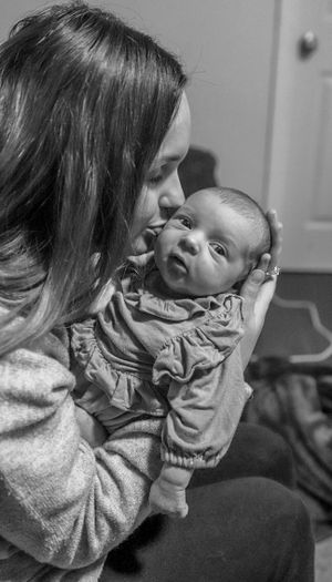 A tender moment between parent and newborn captured in black and white photography.